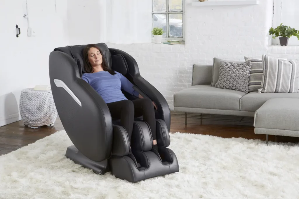 Woman sits slightly reclined in a black Infinity Massage Chair. Exhibited here is massage chair terminology such as "leg rest" and "recline."