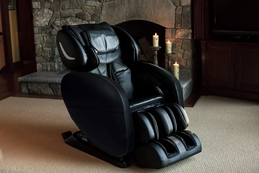A black Infinity Massage Chair sits in front of a fireplace in a living room. An important option to weigh in selecting a luxury massage chair is L-Track vs S-Track Massage Chairs in addressing your physical needs.