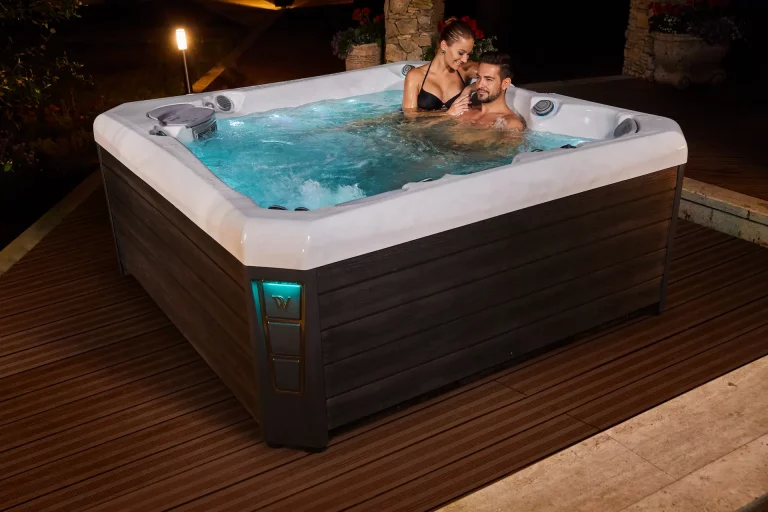 Two people sit in a Wellis Hot Tub on a luxurious patio at night. Choosing a spa, like this one, requires answering fundamental questions about your wellness goals and what you are willing to invest.