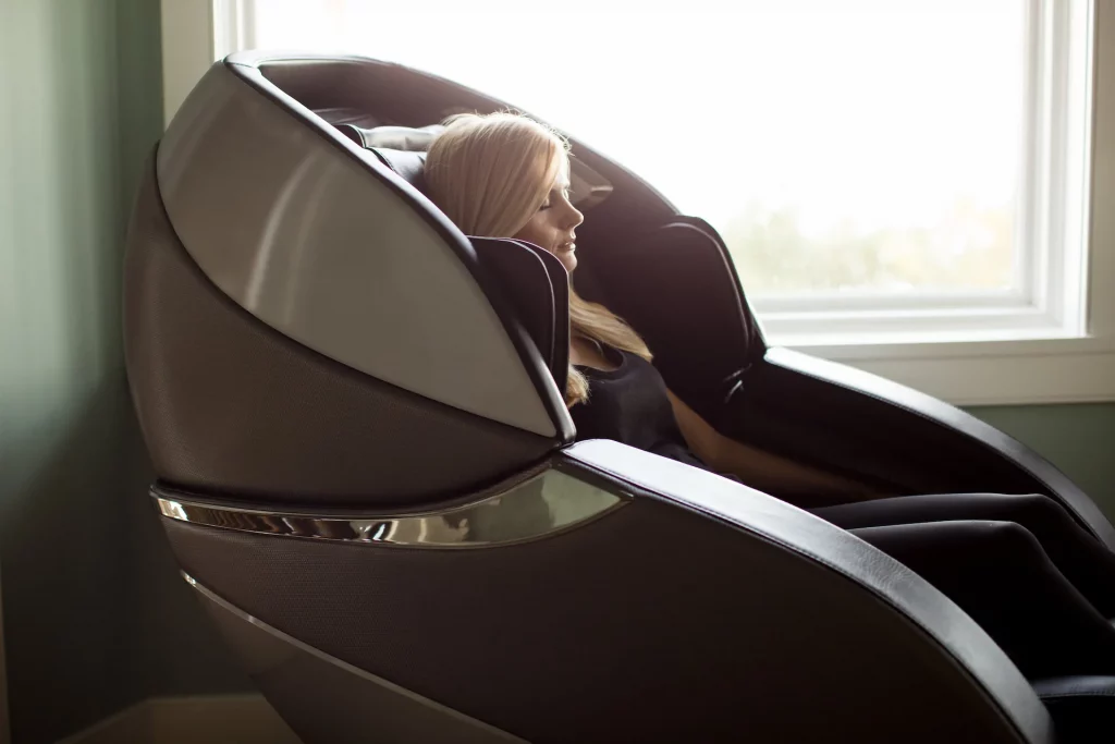A person sitting in an Infinity Massage Chair closes their eyes while enjoying a decompressing back massage. Spinal decompression and stress reduction are two of many massage chair health benefits.